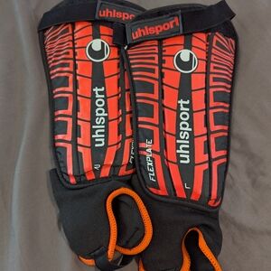 Orange and Black Uhlsport Shin Guards with Geometric Design